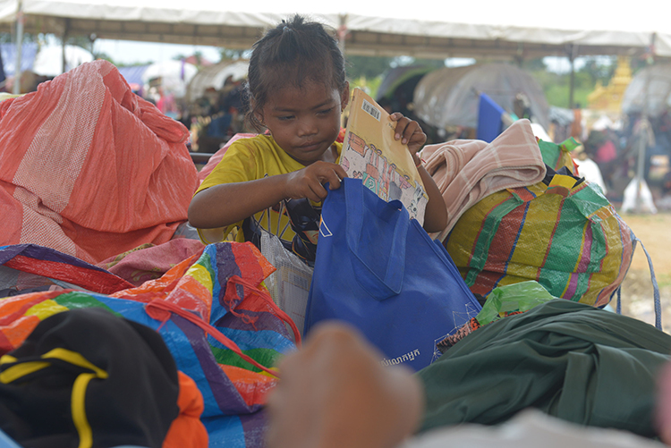 EDGE Worldwide border crisis response: a displaced Cambodian child opens an EDGE Worldwide supply package at a shelter near the Cambodia-Thailand border